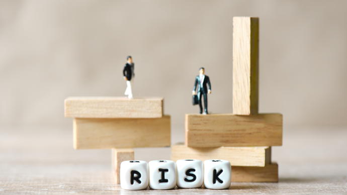 to figurer balanserer på klosser, terninger som viser ordet "risk"