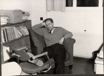 Professor Aubert sitter i en lenestol på kontoret. Bokhyller.