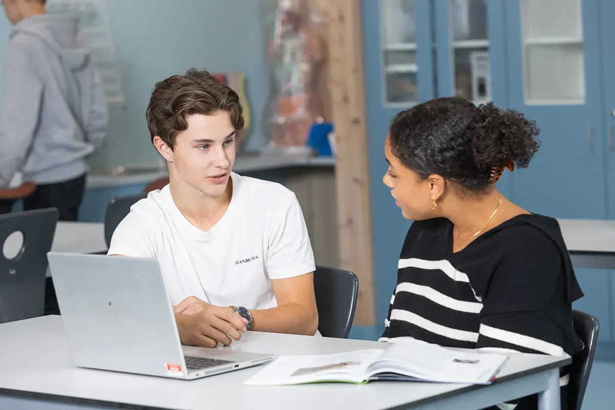 To tiandeklassingar, ein gut og ei jente, sit ved ein PC og diskuterer