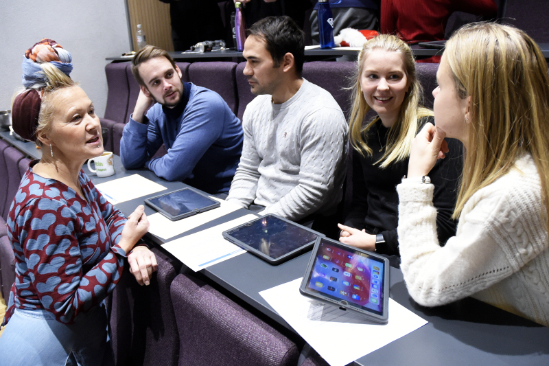 Fem lærere sitter og diskuterer på en rad i et auditorium