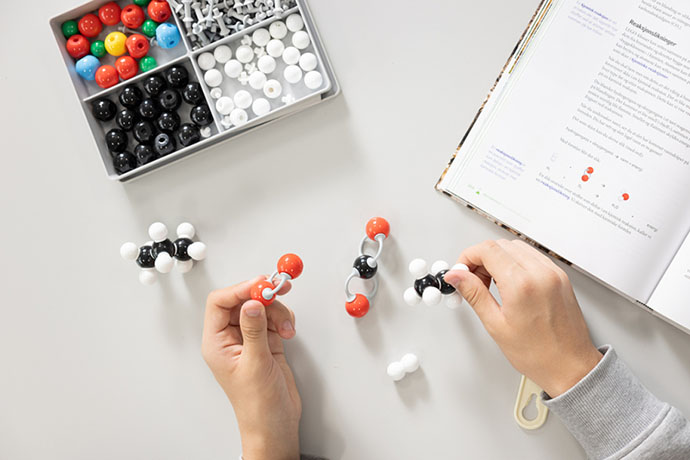 Vi ser hendene til en person som byger en atommodell