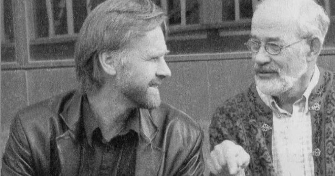 A black-and-white photo of two men having a discussion. 