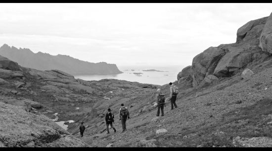 A black-and-white photo of a couple of men walking down the hill on their expedition in Lofoten. 
