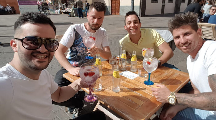 Four men sitting at a coffee table at a plaza in Spain