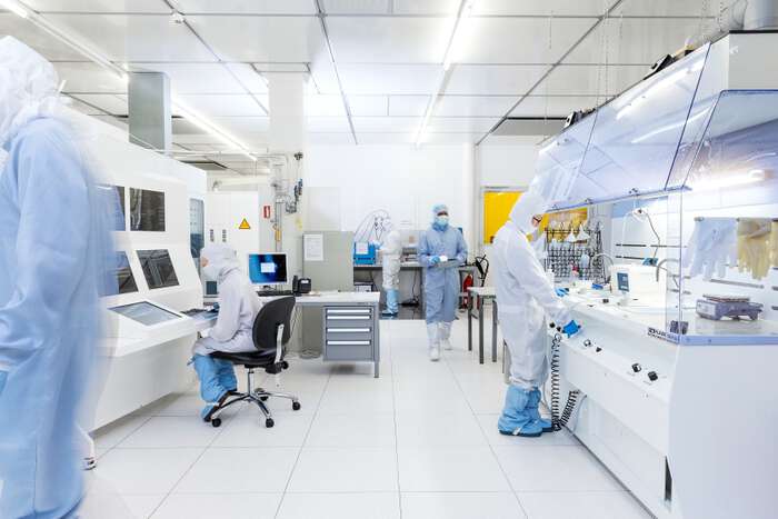 Photo from UiO MiNaLab cleanroom. It shows five people working in the laboratory wearing cleanroom suits.